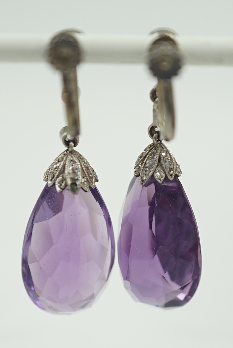 A pair of 1920's platinum?, single stone pear cut amethyst and millegrain round cut diamond set drop ear clips